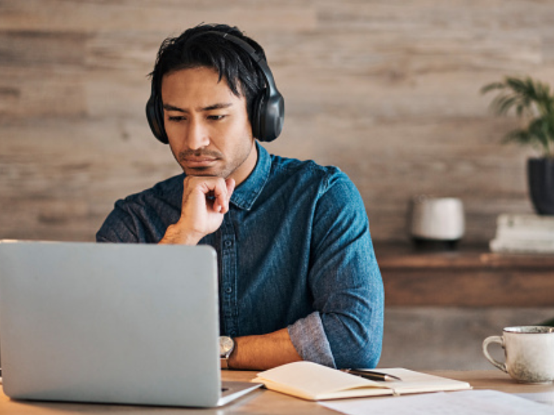 Man wearing headphones on his laptop